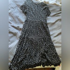 Black dress with white flowers on it. Has button on the back. NEVER BEEN WORN!